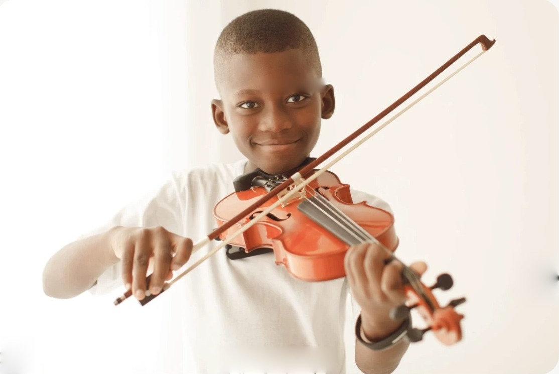 Aluno do Musicarium sorrindo enquanto toca violino.