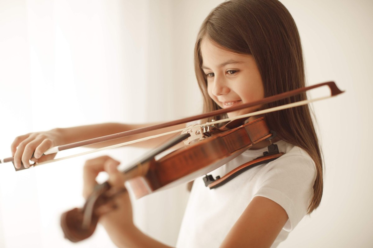 Menina sorrindo enquanto toca violino