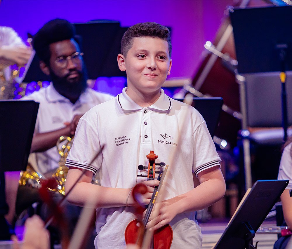 Aluno do Musicarium com violino no palco do concerto