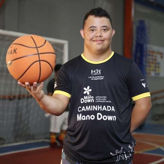 Atleta do Instituto Mano Down sorrindo com uma bola de basquete na mão