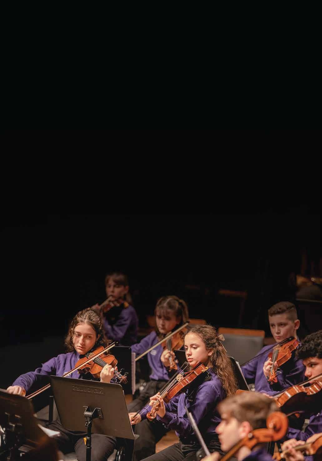 Jovens violinistas do Musicarium em apresentação de orquestra.