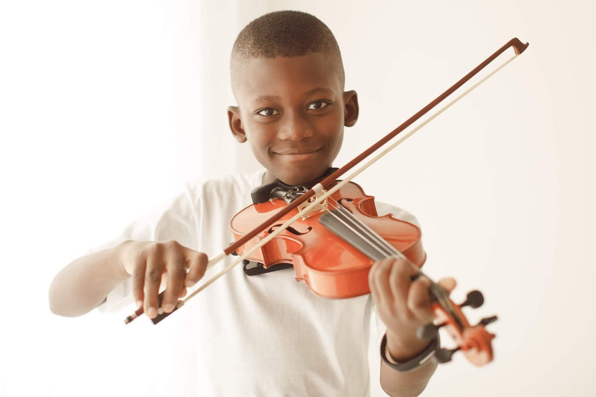 Menino sorrindo enquanto toca violino